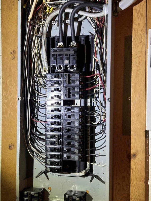 Conducted comprehensive electrical assessment of 1955-era residential property following water damage discovery during wall demolition. Evaluated existing electrical panel, circuit breaker configuration, and branch circuit wiring to determine code compliance requirements. Documented current electrical infrastructure including main service panel mounted between wall studs, circuit breaker arrangement, conductor routing, and overall system organization. Inspected wire bundling at panel entry point, verified breaker capacity distribution, and assessed condition of existing conductors. Photographed electrical panel installation, wire management, and connections to provide detailed documentation for code upgrade estimate. Identified potential areas requiring remediation to meet current National Electrical Code standards for aged residential electrical systems.