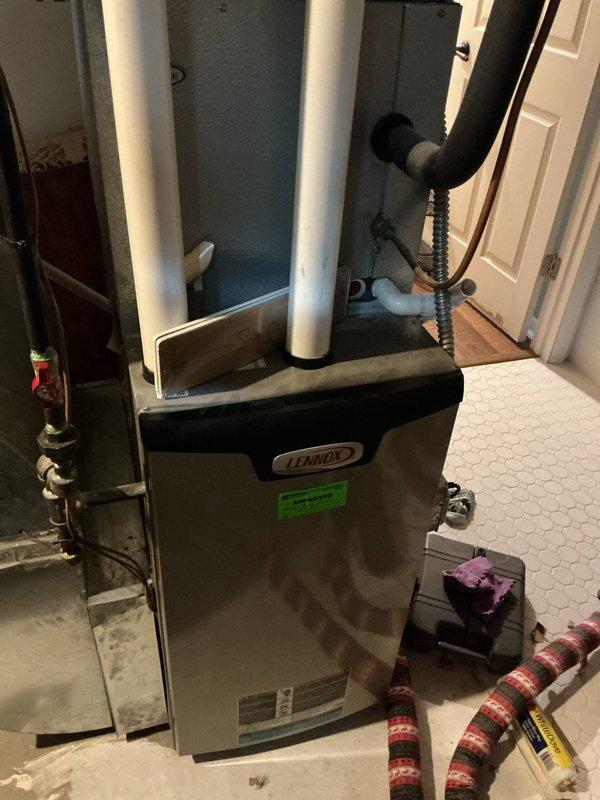 Responded to storm damage affecting the furnace vent system on an 11-year-old Lennox unit. Inspected roof-mounted vent pipe and flashing assembly, which showed weather-related displacement and compromised sealing. Examined indoor furnace installation, confirmed PVC intake and exhaust venting configuration, and verified all connections were secure. Documented existing conditions with photographs of both the roof penetration and the furnace unit in the mechanical closet. Assessed the vent cap, flashing plate, and roofing sealant for integrity. Provided customer with findings and recommendations for necessary repairs to restore proper venting function and prevent potential safety hazards or water intrusion before operating the heating system.