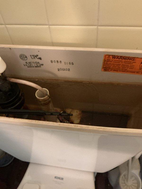 Responded to report of constant dripping leak in toilet ongoing for one week to one month in 1934-built home. Removed tank lid and inspected Kohler toilet tank components. Found deteriorated flapper valve causing continuous water leak from tank to bowl. Documented existing condition showing mineral deposits and discoloration throughout tank interior, worn red rubber flapper, and dated fill valve assembly. Photographed tank interior components including flush valve, overflow tube, and manufacturing date code indicating unit from 2001. Replaced failed flapper valve with new component to restore proper seal and eliminate constant water flow.