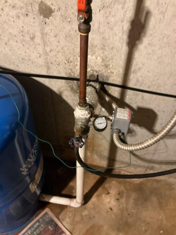 Responded to a slow leak at well pressure tank in a 55-year-old residential property. Upon inspection, discovered active leak at pressure tank connection point that had likely been occurring for 1-2 weeks based on visible water damage and mineral deposits around the affected area. The system consisted of a Water Worker brand pressure tank with copper and PVC plumbing connections, pressure control unit, and associated shut-off valves.

Isolated the well system using the existing shut-off valves and depressurized the tank to safely access the leak source. Identified the leak originating from a compromised fitting connection between the copper supply line and the pressure tank inlet. Removed the faulty connection, cleaned and prepared pipe threads, and installed new brass fitting with proper thread sealant and torque specifications. Verified all surrounding connections for integrity and tightened the blue manual valve that showed signs of minor seepage.

Restored water pressure to the sys
