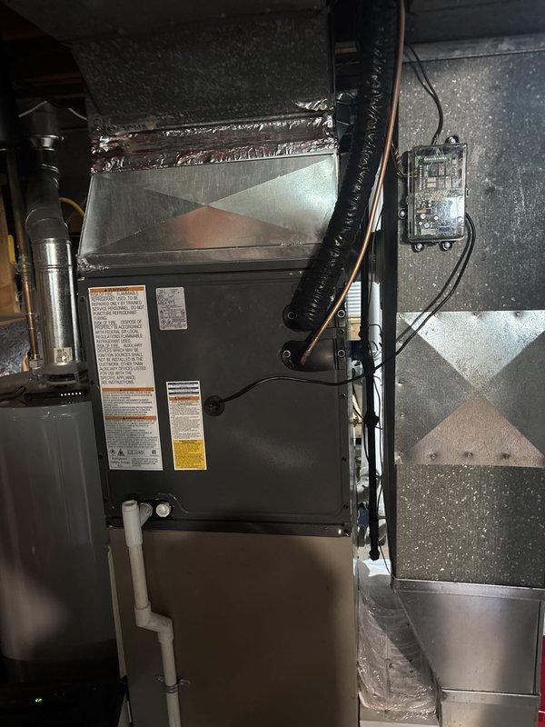 Completed full residential air conditioning system replacement including outdoor condensing unit and indoor air handler. Removed existing equipment and installed new condenser on concrete pad against exterior wall with proper electrical disconnect box and conduit connections. Installed new air handler in basement utility space with associated ductwork connections and electrical controls. Verified proper refrigerant lines, drainage, and all electrical connections to code. System tested and operational upon completion.