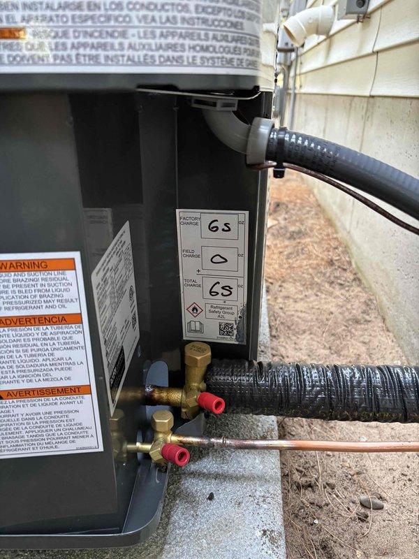 Successfully completed full air conditioning system replacement at residential property. Removed existing outdoor condensing unit and installed new Amana condenser on concrete pad adjacent to building exterior. Ran new refrigerant line set with proper insulation from outdoor unit to interior air handler, utilizing gray foam insulation on copper lines. Installed electrical disconnect box on exterior wall with appropriate conduit routing for power supply. Connected refrigerant lines with brass fittings and service valves, properly capped and secured all connections. Installed new PVC condensate drain line from unit through building siding. System was pressure tested, evacuated, and charged to manufacturer specifications. Verified all electrical connections, tested unit operation, and confirmed proper airflow through condenser fan assembly. Installation completed per manufacturer guidelines with all safety labels and warnings properly affixed to equipment.