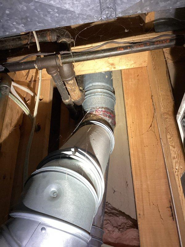 Responded to no hot water call at residential property. Upon arrival, inspected water heater system located in crawl space/basement area. Found water heater approximately 10 years old with complete loss of hot water throughout entire house. Examined plumbing connections, including copper supply lines with insulation, shutoff valves, and flexible connectors. Assessed HVAC ductwork and ventilation system in attic space above water heater location. Documented existing installation with copper piping, blue-handled shutoff valve, braided flex lines, and electrical connections. Evaluated overall system condition and provided recommendations for service or replacement based on age and operational status of unit.