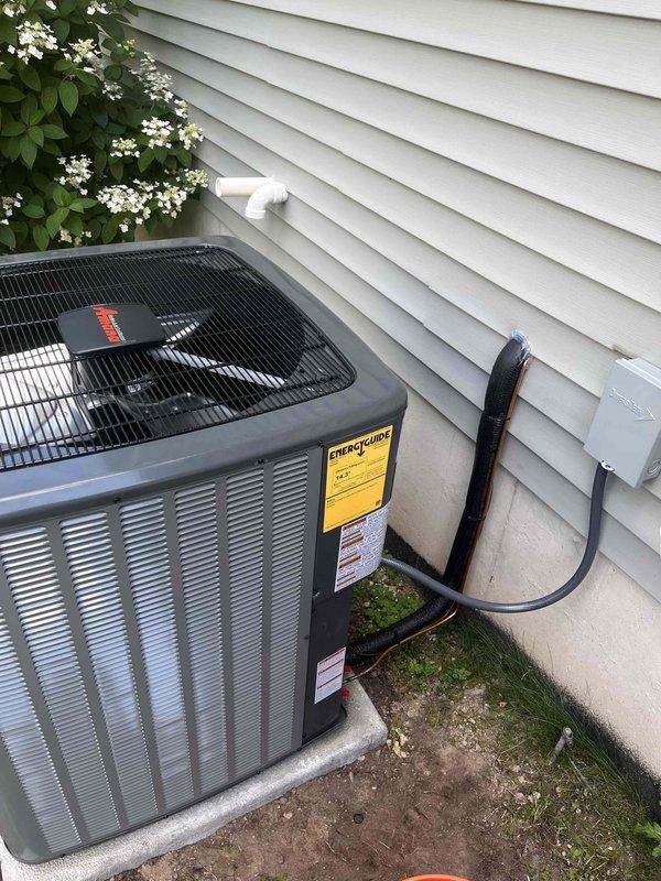 Completed full HVAC system replacement including outdoor condensing unit and indoor air handler components. Installed new gray outdoor AC unit on existing concrete pad against exterior wall with proper electrical disconnect and conduit routing through white vinyl siding. Mounted Lennox indoor equipment in mechanical closet below existing black furnace unit, ensuring proper integration with current heating system. Configured all necessary PVC condensate drainage lines and established proper clearances for service access. Verified all manufacturer labels and EnergyGuide documentation properly affixed to equipment. System tested and confirmed operational upon completion.