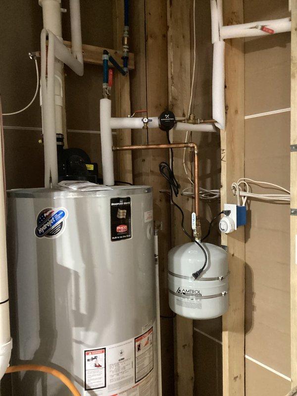 Responded to complaint of sporadic hot water and loss of heat mid-shower in five-year-old home. Upon inspection, discovered significant corrosion and mineral buildup on copper piping connections at water heater inlet. Identified compromised fitting restricting water flow to unit, causing inadequate hot water delivery throughout residence. Documented existing plumbing configuration including expansion tank and valve assembly. Recommended immediate replacement of corroded copper fittings and evaluation of water heater dip tube for potential deterioration contributing to inconsistent hot water supply.