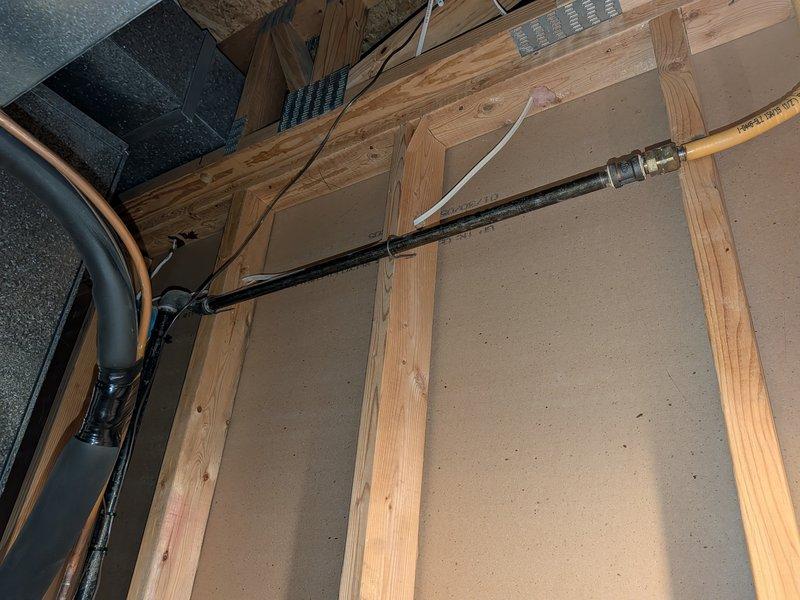 Responded to noise complaint regarding air conditioning system creating loud sounds through interior wall. Upon inspection, located source of noise in attic space where refrigerant lines and ductwork were improperly secured to wooden framing members. Found that vibration from compressor operation was being transmitted through inadequately fastened black insulated refrigerant line, causing resonance against wall studs and creating audible disturbance in living space. Properly secured all refrigerant lines with appropriate mounting brackets and added vibration-dampening isolation between pipes and framing to eliminate noise transfer. Verified system operation and confirmed noise issue resolved.