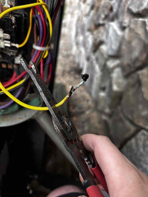 # Air Conditioner Not Cooling

Responded to no cooling complaint on residential air conditioning system. Upon inspection, discovered failed dual run capacitor with severely corroded terminals and evidence of electrical arcing. Terminal connections displayed heavy oxidation, burnt residue, and heat damage. One capacitor wire exhibited significant thermal damage with melted insulation and charring, indicating electrical failure under load.

Removed defective capacitor and damaged wiring. Installed new dual run capacitor with proper microfarad rating for compressor and condenser fan motor. Replaced burnt wire with appropriate gauge conductor and made secure connections to new capacitor terminals. Applied dielectric grease to terminal connections to prevent future corrosion. Verified all electrical connections were tight and properly insulated.

Energized system and confirmed compressor and outdoor fan motor operation. Measured supply voltage, amp draw on both circuits, and verified capaci