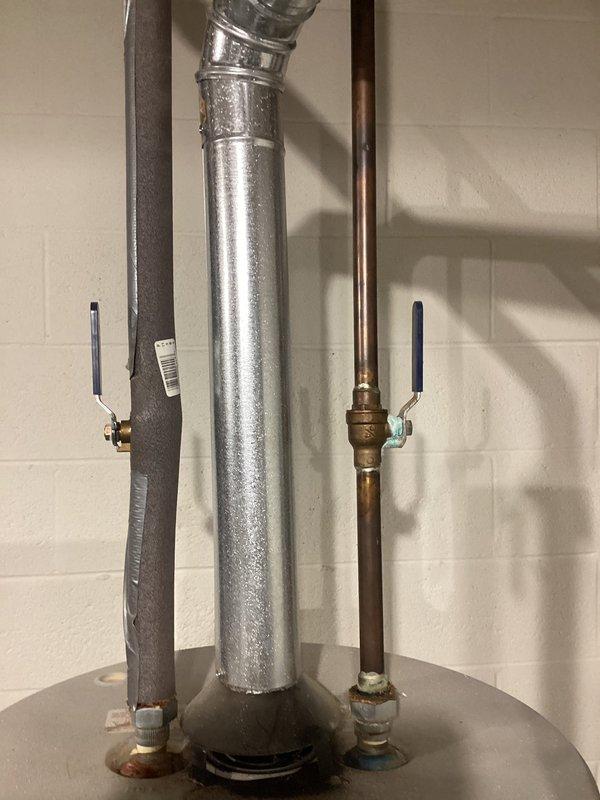 Provided estimate for replacement of existing 23-year-old 50-gallon conventional storage water heater with tankless water heating system for ranch-style residence. Evaluated current installation including venting configuration, gas supply line, and plumbing connections to determine requirements for tankless conversion capable of supporting whole-home demand with simultaneous operation of up to three shower fixtures. Documented existing equipment specifications and photographed current water heater installation showing top-mounted connections, flue pipe, and utility room layout to assess necessary modifications for tankless unit installation.