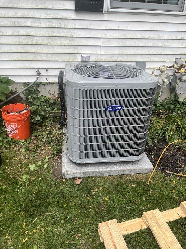 Completed full HVAC system replacement including outdoor condensing unit and indoor furnace. Installed new Carrier brand air conditioning condenser on existing concrete pad against exterior wall with proper clearances maintained. Unit positioned on stable foundation with adequate airflow access and protection from landscaping debris. Removed old equipment and set new outdoor unit with refrigerant line connections, electrical hookup, and condensate drainage properly configured.

Installed matching Carrier furnace in basement utility area with complete ductwork integration. Connected white PVC venting system with proper pitch and termination, installed gas line connections, and completed electrical wiring to code. Integrated system controls and verified all safety switches operational. Tested furnace ignition sequence, blower operation, and airflow distribution throughout duct system.

Charged refrigerant system to manufacturer specifications and verified proper subcooling and superheat 
