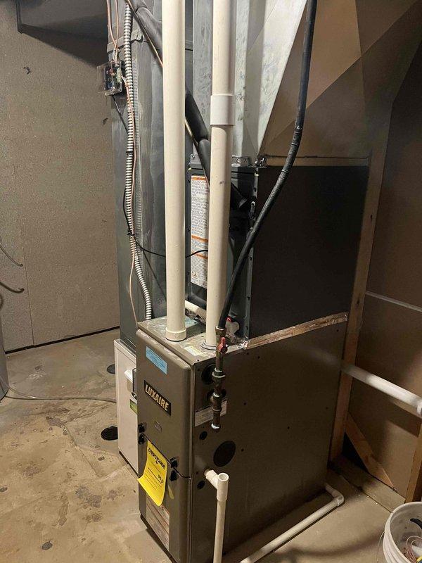 Completed full HVAC system replacement including removal of existing equipment and installation of new Luxaire furnace in basement utility area and matching outdoor condensing unit. Installed refrigerant line set with proper insulation, established all electrical connections with disconnect box, and ran PVC condensate drainage lines with appropriate venting. Positioned outdoor unit on concrete pad with gravel surround for proper drainage and clearance. System tested and verified operational with all safety controls functioning correctly.