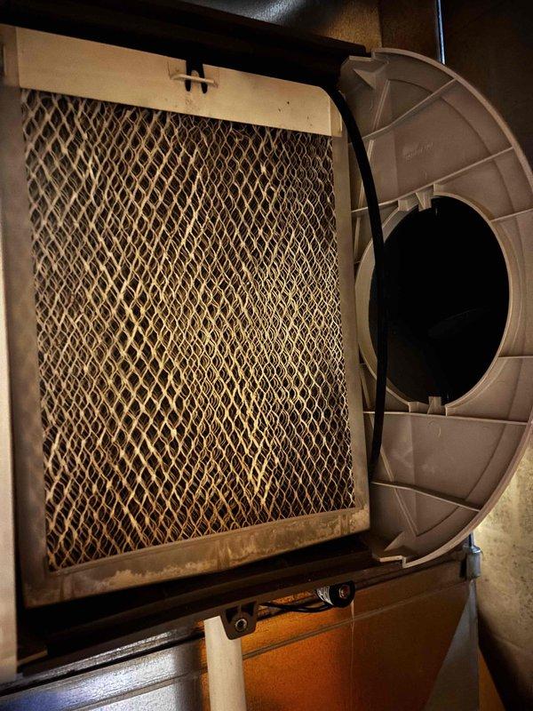 Responded to reported water leak concern at property with 8-year-old AC unit and 9-year-old furnace (EnergiAir systems with warranties through 2027-2028). Upon inspection, examined HVAC system components including air filter and blower assembly, which showed normal dust accumulation consistent with system age. Inspected utility room area including water heater, PVC drainage lines, and concrete floor surfaces. Documented visible water staining and moisture patterns on floor near mechanical equipment. Verified heating system remained operational during inspection. Photographed filter condition, blower housing, water heater installation, and floor areas showing staining to document current system condition and identify potential leak source for further evaluation.