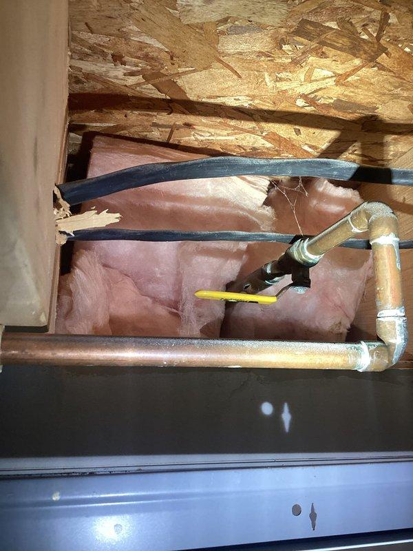 Responded to plumbing leak involving copper supply line serving exterior hose bib. Upon inspection, discovered burst pipe that sustained freeze damage during winter months. Accessed affected piping in concealed space above finished area where copper line runs through framing cavity with insulation. Removed damaged section of copper pipe and installed new copper piping with proper fittings and connections. Utilized brass elbow fittings and shut-off valve to complete repair and restore water control functionality to exterior hose attachment. Tested system for leaks and verified proper water flow and shut-off operation. Documented existing conditions and completed repairs with photographic evidence.