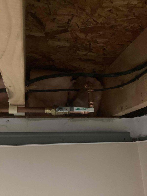 Responded to plumbing leak involving copper supply line serving exterior hose bib. Upon inspection, discovered burst pipe that sustained freeze damage during winter months. Accessed affected piping in concealed space above finished area where copper line runs through framing cavity with insulation. Removed damaged section of copper pipe and installed new copper piping with proper fittings and connections. Utilized brass elbow fittings and shut-off valve to complete repair and restore water control functionality to exterior hose attachment. Tested system for leaks and verified proper water flow and shut-off operation. Documented existing conditions and completed repairs with photographic evidence.