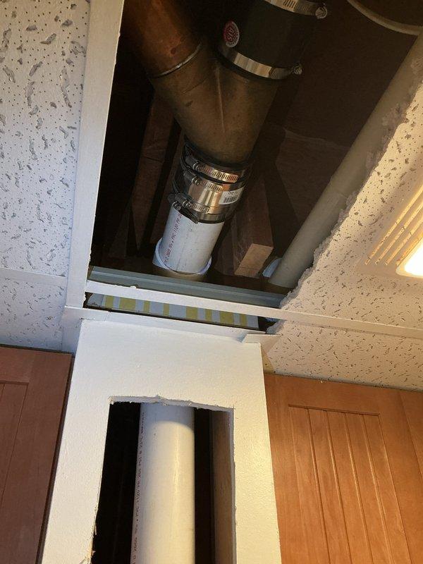 Completed stack-only replacement in residential ceiling cavity, removing existing deteriorated plumbing stack and installing new white PVC pipe assembly with proper coupling connections and securing clamps. Accessed work area through ceiling panel opening, connected new vertical drain stack to existing metal ductwork and lower plumbing system, ensuring proper alignment and watertight seals throughout installation.