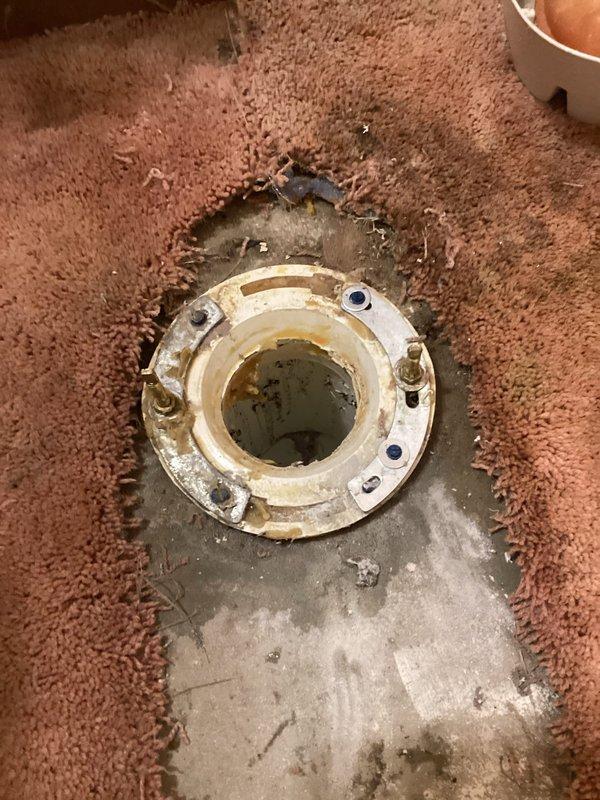 Responded to service call for loose toilet that was moving when sat upon. Upon inspection, found toilet flange bolts had loosened, causing instability in the fixture. Removed toilet to access flange assembly and assessed the installation. Tightened flange bolts securely to the concrete subfloor, ensuring proper anchoring. Inspected wax ring seal and flange condition for any damage or deterioration. Reset toilet onto flange with proper alignment, secured closet bolts, and torqued nuts evenly to manufacturer specifications to eliminate movement. Tested stability by applying pressure to confirm secure installation. Documented existing water damage staining on concrete subfloor and worn carpet condition around flange area for client's awareness.