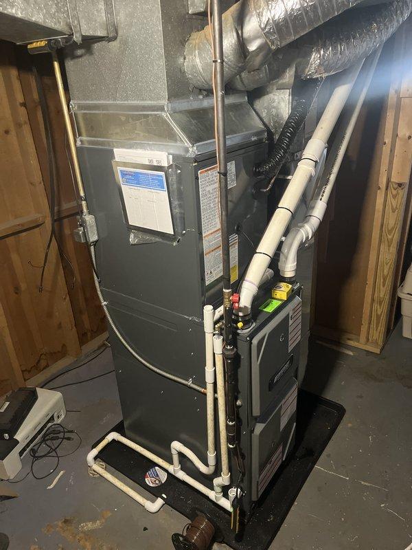 Completed full air conditioning system replacement including outdoor condensing unit and indoor air handler components. Installed new Amana condenser unit on existing concrete pad with proper clearances from exterior walls. Connected refrigerant lines, electrical service, and condensate drainage system with new PVC piping routed to appropriate discharge location. Mounted and secured indoor air handler adjacent to existing furnace in basement utility area with properly installed flexible ductwork connections. Verified all electrical connections, tested system startup and operation, confirmed proper refrigerant charge and airflow, and ensured all components functioning within manufacturer specifications.