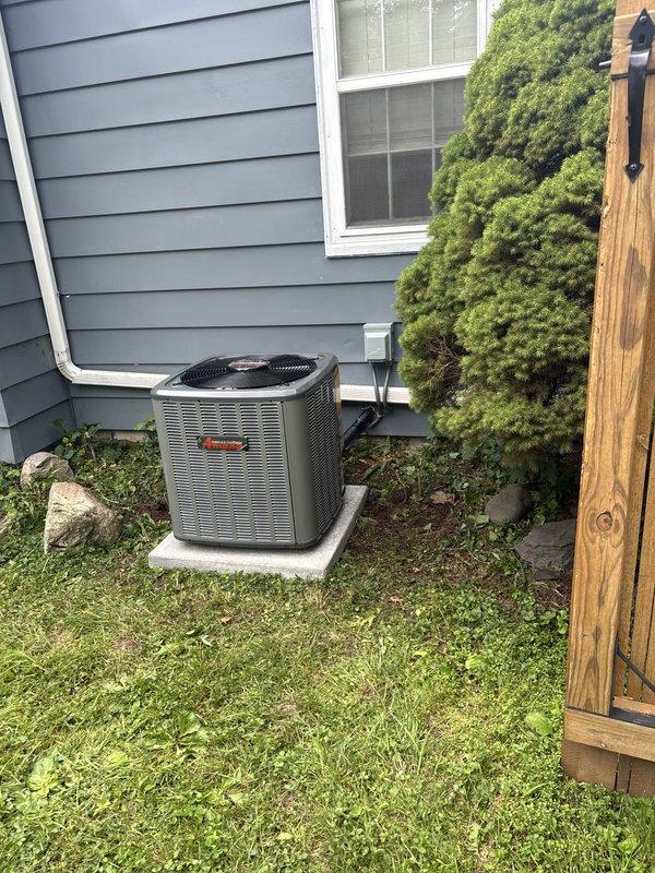 Completed full air conditioning system installation including outdoor condensing unit and indoor evaporator coil integration with existing forced-air furnace. Installed Trane brand condensing unit on concrete pad adjacent to home exterior, positioned near existing landscaping with proper clearances maintained. Ran refrigerant line set and electrical connections from outdoor unit through exterior wall penetration to basement mechanical room. Integrated new evaporator coil with existing furnace plenum and ductwork system. Installed condensate drain line with proper pitch and termination. Connected and secured all refrigerant lines with appropriate insulation. Completed electrical wiring to outdoor disconnect and indoor air handler connections. Evacuated refrigerant lines to manufacturer specifications, pressure tested system for leaks, and charged unit with proper refrigerant type and quantity. Verified proper airflow across evaporator coil and confirmed compatibility with existing April
