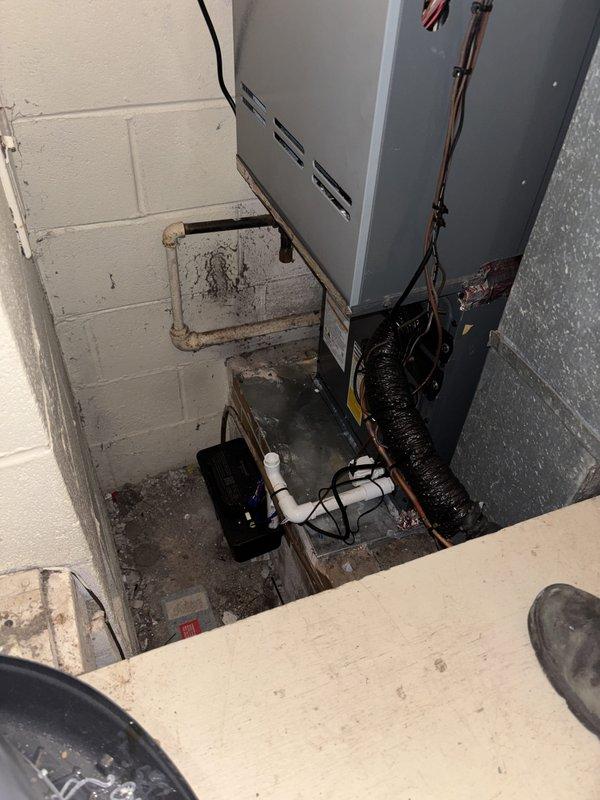 Completed full air conditioning system replacement including outdoor condensing unit and indoor air handler. Removed existing equipment and installed new HVAC system with proper refrigerant line connections, electrical disconnect, and condensate drainage. Positioned outdoor unit on concrete pad against exterior brick wall with appropriate clearances. Installed indoor air handler in basement mechanical room with black flexible ductwork connections and white PVC condensate piping. Verified all electrical connections, tested system operation, and confirmed proper cooling functionality upon completion.