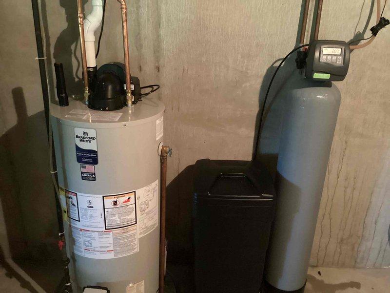 Responded to no hot water complaint. Upon arrival, inspected Bradford White water heater and associated plumbing system in basement utility area. Evaluated water heater operation, electrical connections, and gas supply. Confirmed water softener and filtration system were functioning properly with digital control head displaying normal operation. Checked copper supply lines, shutoff valves, and verified proper water flow through the system. Diagnosed issue and restored hot water service to the residence.