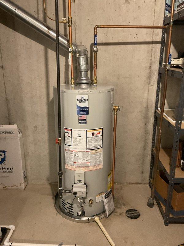 Completed installation of a 40-gallon natural gas Bradford White water heater in basement utility area. Connected copper supply and discharge piping with brass fittings, installed expansion tank on cold water line, and verified proper gas control assembly operation. All plumbing connections tested and confirmed leak-free with unit operational at time of departure.
