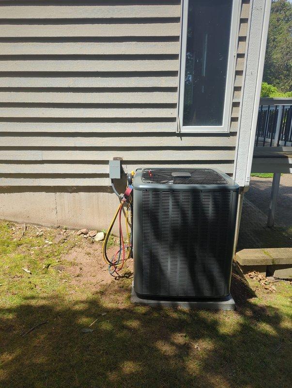 Complete installation of new furnace and air conditioning system. Outdoor condensing unit positioned on concrete pad with proper refrigerant line connections running through exterior wall. System charged with R-32 refrigerant per manufacturer specifications at 180 oz factory charge. All refrigerant connections, valves, and fittings properly secured and tested for leaks.
