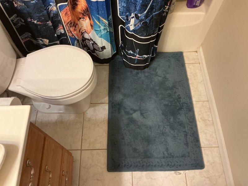 Responded to toilet leak affecting kitchen ceiling below bathroom in 18-year-old residence. Upon inspection, identified active water intrusion originating from toilet area that had been occurring for 1-2 days. Examined toilet installation, wax ring seal, water supply line connections, and floor flange for source of leak. Documented conditions with photographs showing bathroom layout, toilet positioning, flooring condition, and water supply configuration to establish baseline and identify potential failure points requiring repair.