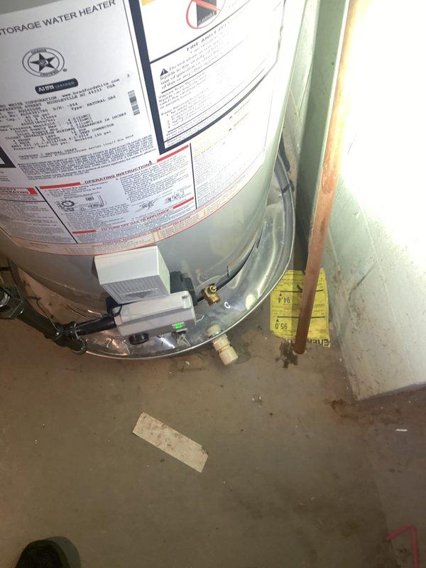 Responded to water leak alarm triggered by water accumulation in drain pan beneath Bradford White water heater. Upon inspection, confirmed approximately 1-year-old Bradford White WT 04 unit with water present in safety pan. Examined all visible plumbing connections, copper supply lines, and tank exterior for signs of active leakage or seepage. Documented equipment condition and installation with photographs showing unit positioning, manufacturer labels, plumbing connections, and surrounding utility space conditions. Verified drain pan alarm functionality and monitored for continued water accumulation to determine leak source.