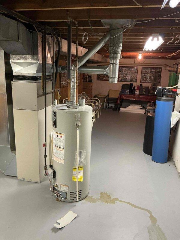 Responded to no hot water complaint at residential property. Upon inspection, found 11-year-old water heater with active leak from bottom of tank and visible corrosion, with rusty water pooled on concrete floor around base of unit. Water heater had reached end of serviceable life with internal tank failure causing the leak. Documented equipment condition and leak location with photos. Advised customer of findings and recommended full water heater replacement due to tank integrity failure.