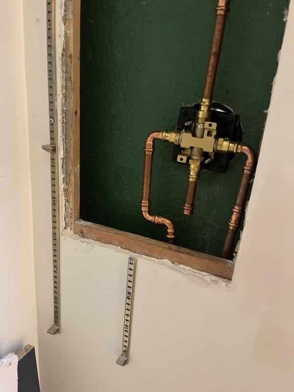 Responded to repair request for loose shower head arm and lever handle in 1950s-era home prior to property sale. Accessed shower valve assembly by opening wall cavity to expose plumbing infrastructure. Secured copper pipe assembly and brass valve connections, reinforced mounting points, and stabilized loose components to eliminate movement in shower arm and handle lever. Restored proper fixture stability and completed repairs to meet buyer's inspection requirements.