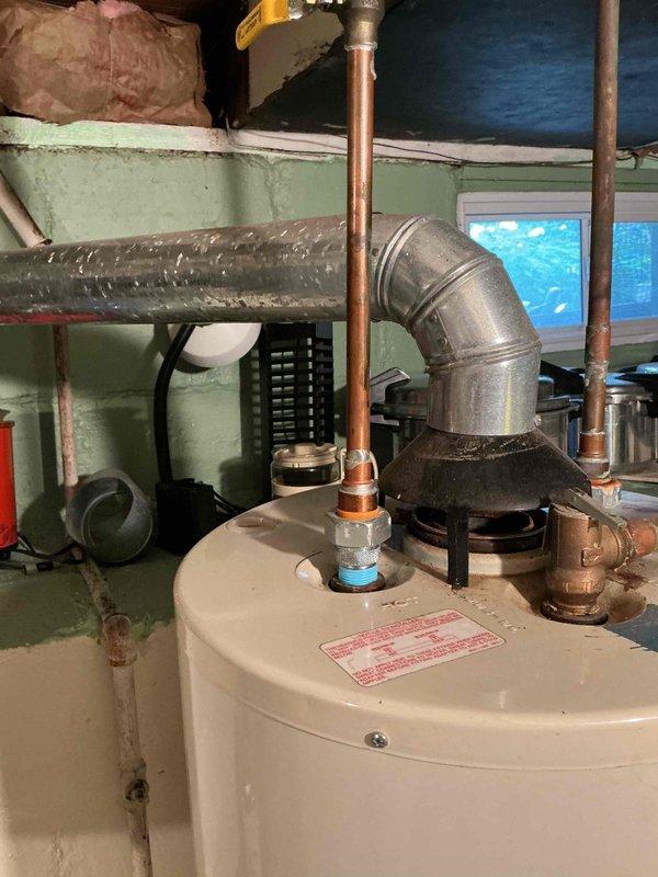 Conducted water heater estimate in basement utility area. Inspected existing aged cylindrical water heater with multiple copper supply lines, brass fittings, and yellow-handled shutoff valve. Documented current installation including connection points, venting configuration with metallic ductwork, and surrounding plumbing infrastructure. Assessed mechanical room conditions and photographed equipment for replacement proposal.