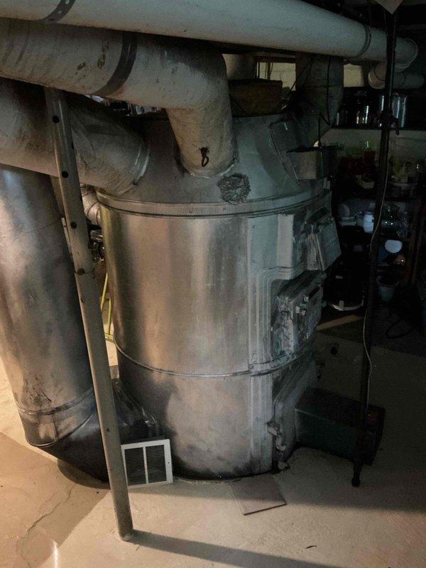 Conducted water heater estimate in basement utility area. Inspected existing aged cylindrical water heater with multiple copper supply lines, brass fittings, and yellow-handled shutoff valve. Documented current installation including connection points, venting configuration with metallic ductwork, and surrounding plumbing infrastructure. Assessed mechanical room conditions and photographed equipment for replacement proposal.
