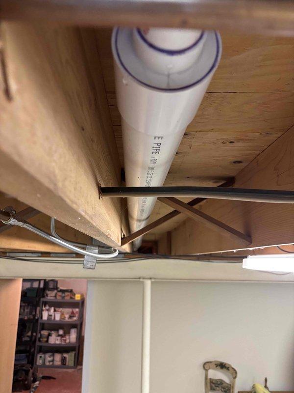 Completed installation of new kitchen drain line with connection to existing bathroom stack in basement area. Ran white PVC drainage pipe from kitchen location through floor joists, routing horizontally through ceiling structure before tying into vertical bathroom waste stack. Secured all piping with proper hangers and strapping per code requirements. Work included cutting and fitting PVC components, creating watertight connections, and ensuring proper slope for drainage. All exposed plumbing in unfinished basement area is properly supported and accessible for future maintenance. Installation completed with no obstructions to existing HVAC ductwork or other utilities.
