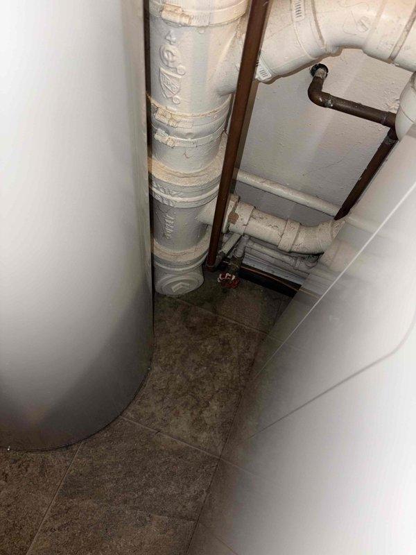 Responded to plumbing leak in utility area of 1940s-era home. Upon inspection, identified active leak at PVC drain connection in basement mechanical room near water heater. Tightened loose fitting at drain elbow joint and inspected surrounding copper supply lines and shut-off valves for additional issues. Verified repair resolved leak and confirmed no water damage to surrounding floor or equipment.
