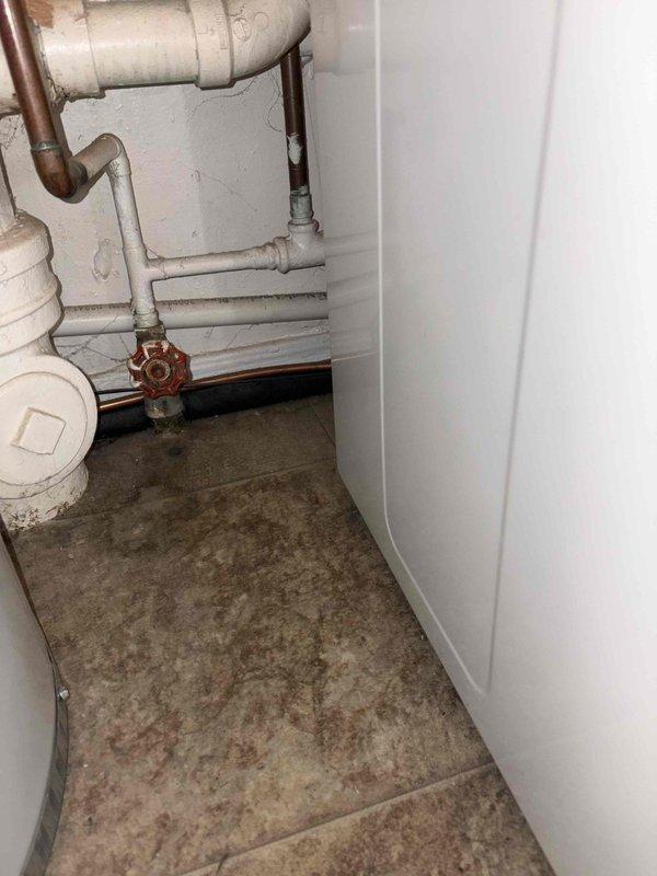 Responded to plumbing leak in utility area of 1940s-era home. Upon inspection, identified active leak at PVC drain connection in basement mechanical room near water heater. Tightened loose fitting at drain elbow joint and inspected surrounding copper supply lines and shut-off valves for additional issues. Verified repair resolved leak and confirmed no water damage to surrounding floor or equipment.