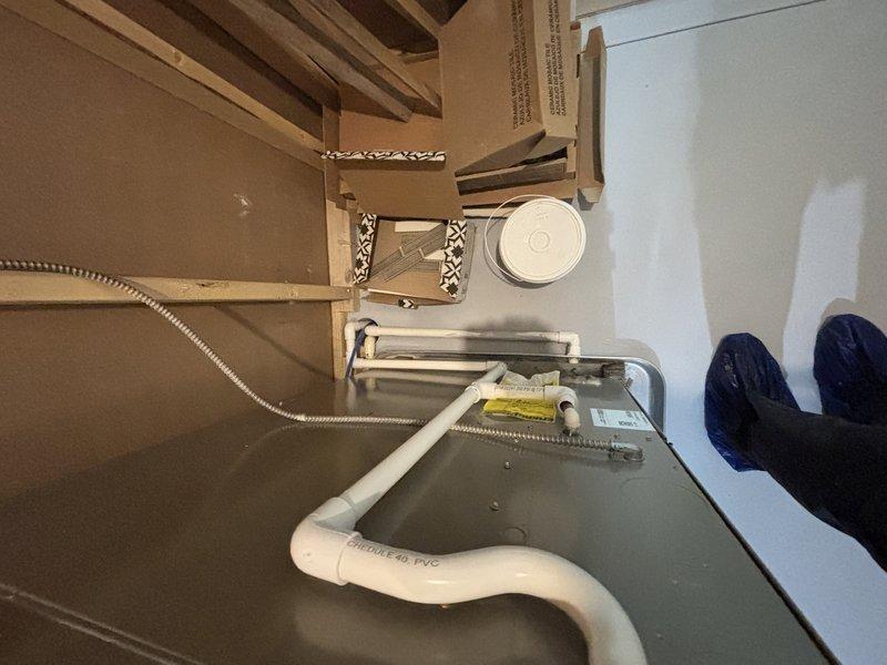 Completed installation of new HVAC system components including furnace, air conditioning unit, and humidifier as part of conversion from single-zone to dual-zone system. Gas furnace with gray metal cabinet was positioned and secured in attic space on prepared work platform with proper clearances maintained. PVC condensate drain line (SCH 40) was routed and installed alongside flexible metallic conduit for proper drainage and electrical connections. All equipment was mounted on wooden framing with cardboard work protection in place during installation. System components were inspected, connections verified, and unit prepared for operational testing upon completion of zone conversion project.