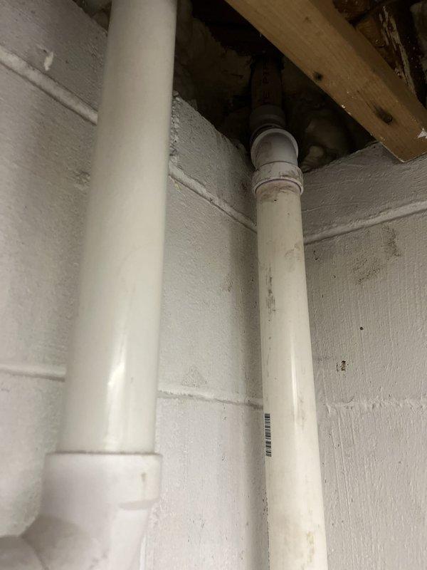 Completed rebuild of kitchen drain line in basement utility area. Installed new white PVC drainage piping running vertically along wall and connecting to existing plumbing infrastructure. Work included proper fitting connections, securing pipes to wall, and ensuring proper drainage flow to floor drain system.