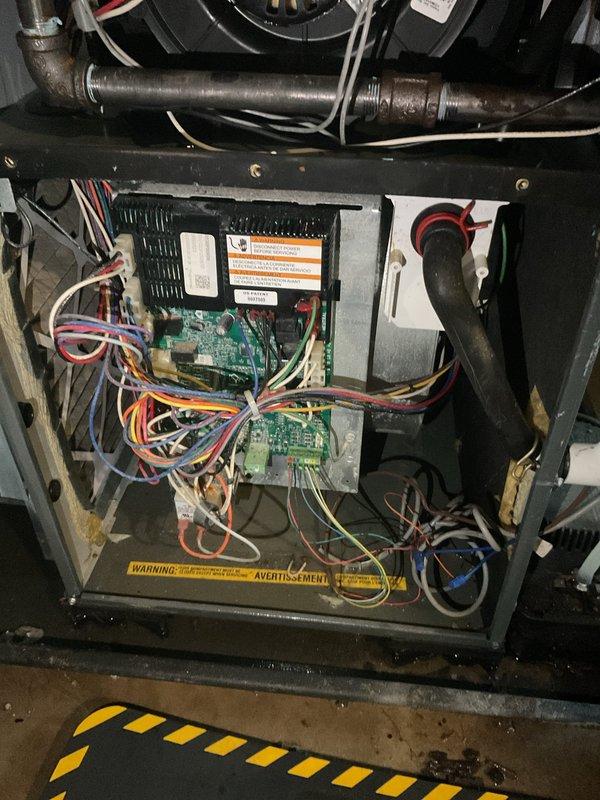 Responded to no cooling call where unit had sustained water damage affecting both furnace and water heater. Upon inspection, found water intrusion had compromised control boards and electrical components within the HVAC system. Documented internal condition of unit showing dual green circuit boards with multiple wire connections, blower assembly, and associated electrical components. Assessed damage to determine extent of water exposure on control systems and mechanical components. Photographed affected areas for documentation and warranty purposes.