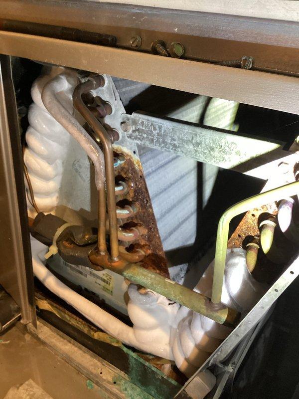 Completed annual cooling maintenance and inspection on residential air conditioning system. Performed comprehensive tune-up including visual inspection of evaporator coil assembly, refrigerant lines, and internal components. Noted significant corrosion and rust on metal brackets, mounting hardware, and copper refrigerant lines throughout the unit, indicating advanced age of the system. Evaporator coils show discoloration and mineral deposits but remain functional. Documented system condition with photographs for customer records. Unit operational at time of departure.
