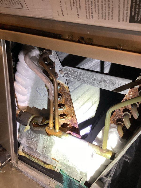 Completed annual cooling maintenance and inspection on residential air conditioning system. Performed comprehensive tune-up including visual inspection of evaporator coil assembly, refrigerant lines, and internal components. Noted significant corrosion and rust on metal brackets, mounting hardware, and copper refrigerant lines throughout the unit, indicating advanced age of the system. Evaporator coils show discoloration and mineral deposits but remain functional. Documented system condition with photographs for customer records. Unit operational at time of departure.