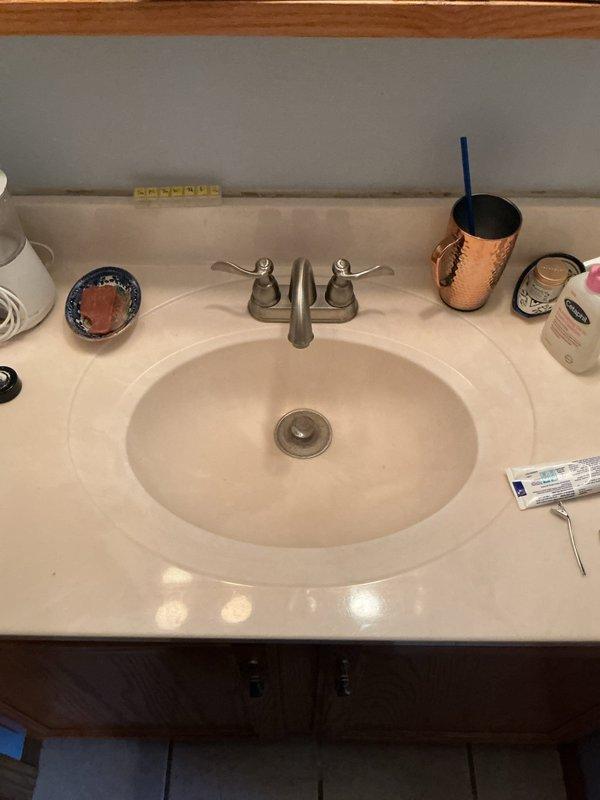 Conducted on-site assessment for complete bathroom remodel and gut project. Documented existing plumbing fixtures including undermount vanity sink with brushed nickel two-handle faucet, standard white porcelain toilet, and evaluated current tile flooring and vanity cabinet condition for full replacement planning.