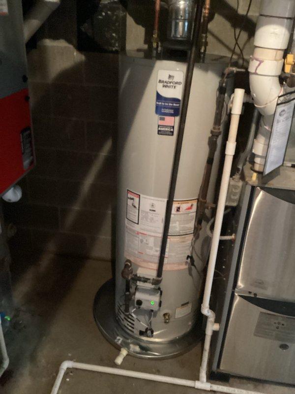 Installed a 50-gallon natural draft Bradford White natural gas water heater in basement utility area. Unit was properly connected to existing gas line and plumbing infrastructure with copper supply lines and appropriate venting, placed on drip pan per code requirements, and tested for proper operation. Installation includes 6-year parts and 1-year labor warranty coverage.
