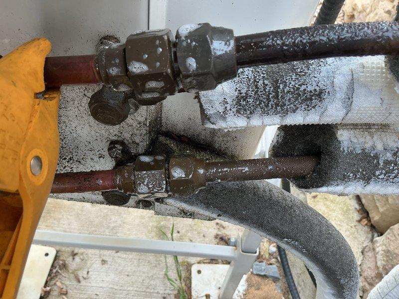 # CP-Cooling Problem

Responded to service call for non-operational lower level mini-split units on a 5-year-old Carrier system. Upon inspection, discovered extensive frost and ice accumulation on refrigerant lines and insulated flex ducts, indicating a refrigerant flow restriction or low refrigerant charge condition. Observed significant condensation buildup on copper piping, aged metal coupling fittings with corrosion, and deteriorated pipe insulation with moisture saturation. Noted shut-off valves on corroded copper lines and evidence of long-term moisture exposure on mounting surfaces and wooden platform areas. Documented system condition with photos showing heavy frost on insulated refrigerant lines, water droplet formation on multiple pipe surfaces, and overall component deterioration consistent with inadequate maintenance and possible refrigerant system issues requiring further diagnostic evaluation and repair.