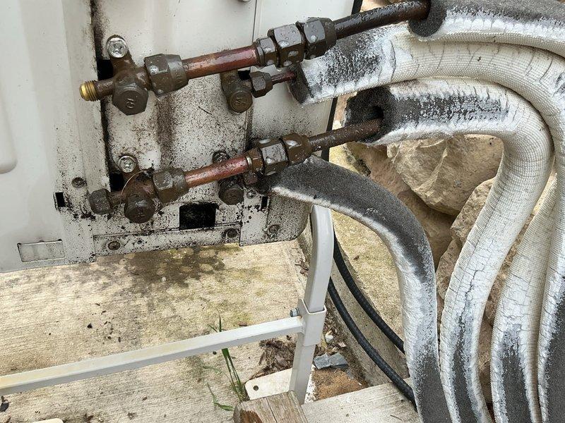 # CP-Cooling Problem

Responded to service call for non-operational lower level mini-split units on a 5-year-old Carrier system. Upon inspection, discovered extensive frost and ice accumulation on refrigerant lines and insulated flex ducts, indicating a refrigerant flow restriction or low refrigerant charge condition. Observed significant condensation buildup on copper piping, aged metal coupling fittings with corrosion, and deteriorated pipe insulation with moisture saturation. Noted shut-off valves on corroded copper lines and evidence of long-term moisture exposure on mounting surfaces and wooden platform areas. Documented system condition with photos showing heavy frost on insulated refrigerant lines, water droplet formation on multiple pipe surfaces, and overall component deterioration consistent with inadequate maintenance and possible refrigerant system issues requiring further diagnostic evaluation and repair.