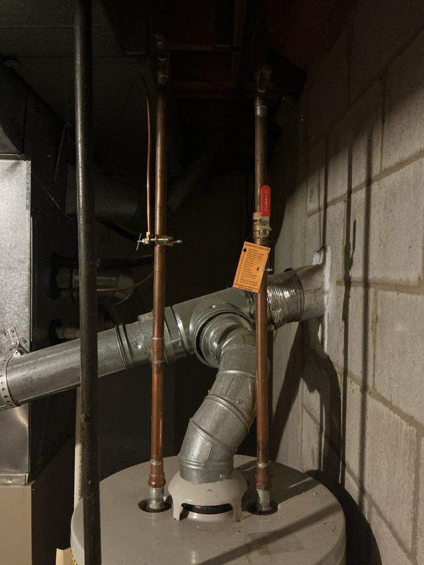 Responded to water leak complaint in basement utility area. Upon arrival, found significant water accumulation on concrete floor surrounding HVAC equipment and water heater installation. Inspected furnace condensate drain pan and associated drainage system. Identified active water discharge from furnace condensate pan due to drainage issue. Documented existing conditions with photographs showing water pooling on floor and plumbing connections. AC system confirmed operational and cooling properly despite drainage concern. Advised tenant to contact property management for necessary repairs per service agreement.
