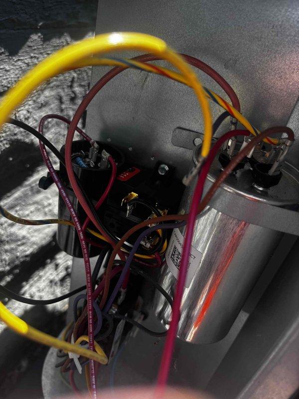 Responded to cooling performance complaint following previous day's maintenance visit where compressor saver device was installed. Evaluated 2-year-old Goodman system and inspected hard start kit installation, verifying proper electrical connections and capacitor wiring configuration. System found operating within normal parameters; confirmed compressor saver device was appropriately installed and functioning correctly to extend equipment lifespan. Explained device purpose and benefits to address customer concerns regarding necessity of component. Documented electrical connections with photographs for service records.