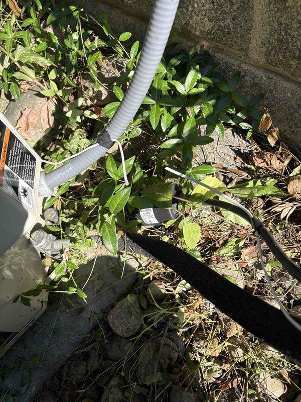 Responded to no cooling complaint and performed diagnostic inspection of outdoor HVAC condensing unit. Upon arrival, found equipment accessible but surrounded by overgrown vegetation and debris that was restricting proper airflow to the unit. Inspected condenser coil, refrigerant lines, electrical connections, and drainage system. Noted corrugated condensate drain line and utility conduits properly routed along building exterior with appropriate mounting hardware. Cleared vegetation and organic debris from around unit perimeter to restore adequate clearance for ventilation and future service access. Verified all exterior piping, conduits, and electrical connections were secure and properly supported. Recommended ongoing vegetation management to prevent airflow restriction and maintain equipment efficiency.