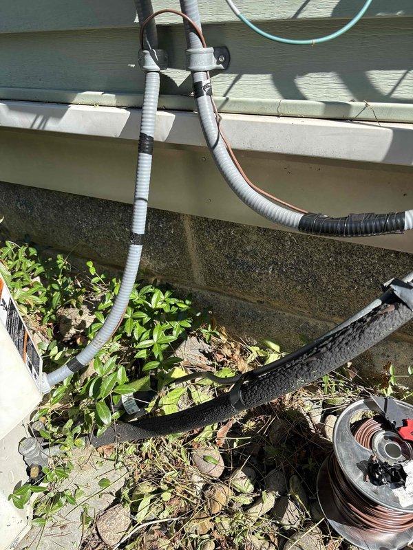 Responded to no cooling complaint and performed diagnostic inspection of outdoor HVAC condensing unit. Upon arrival, found equipment accessible but surrounded by overgrown vegetation and debris that was restricting proper airflow to the unit. Inspected condenser coil, refrigerant lines, electrical connections, and drainage system. Noted corrugated condensate drain line and utility conduits properly routed along building exterior with appropriate mounting hardware. Cleared vegetation and organic debris from around unit perimeter to restore adequate clearance for ventilation and future service access. Verified all exterior piping, conduits, and electrical connections were secure and properly supported. Recommended ongoing vegetation management to prevent airflow restriction and maintain equipment efficiency.