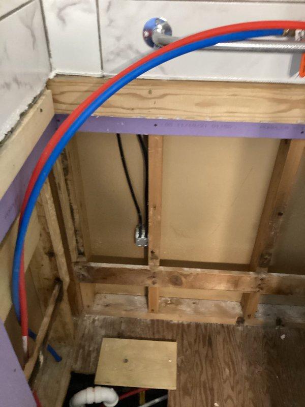 Responded to electrical code compliance concern regarding outlet placement in bathroom shower area. Conducted on-site inspection and documented existing conditions with photographs. Verified that electrical outlet location does not meet current NEC requirements for bathroom installation, as receptacle is positioned within prohibited zone near water source. Assessed rough plumbing installation showing active construction with PEX water supply lines and identified non-compliant outlet mounted on wall in proximity to shower enclosure. Prepared estimate for relocating electrical outlet to code-compliant location outside shower area and replacing receptacle to meet current safety standards.