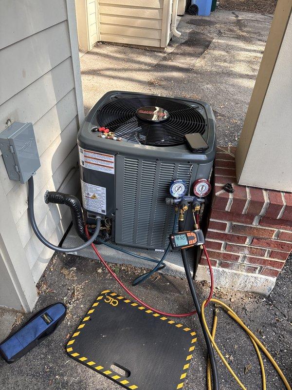 Complete air conditioning system replacement performed at residential property. Removed existing outdoor condensing unit and installed new HVAC condenser on concrete pad between exterior walls. Unit positioned with proper clearances from building structures and electrical disconnect box. 

System startup procedures completed including refrigerant charging verification using manifold gauges with digital readout. Factory charge levels confirmed and documented at charging ports. All refrigerant connections pressure-tested and sealed. Copper refrigerant lines properly insulated and secured. System cycled through complete operation to verify proper function of condenser fan motor and compressor. Final system diagnostics confirmed proper pressures and operational parameters within manufacturer specifications.