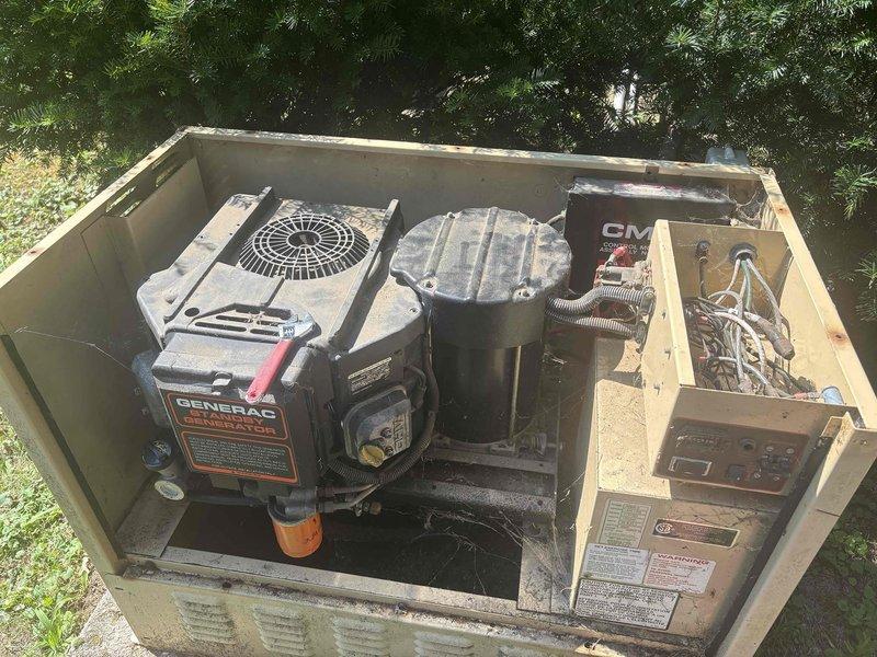Responded to service call for non-operational Generac generator approximately 10 years old. Upon arrival, performed visual inspection of unit with enclosure access panel removed to assess internal components including engine assembly, fuel system, and electrical connections. Documented current condition of generator system showing weathered exterior housing and mechanical components with signs of age and environmental exposure. Photographed internal configuration including Generac engine unit with cooling fan assembly, cylindrical fuel tank component, and associated electrical wiring and control systems for diagnostic reference and service documentation purposes.